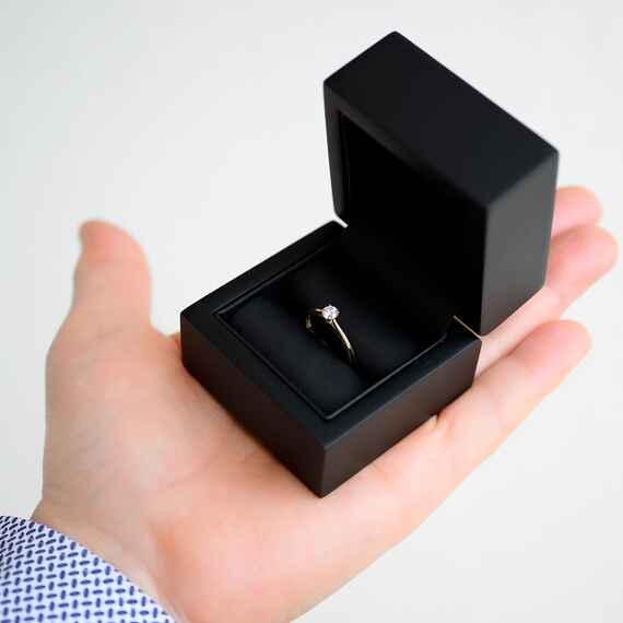 Pudełko czarne na pierścionek na dłoni